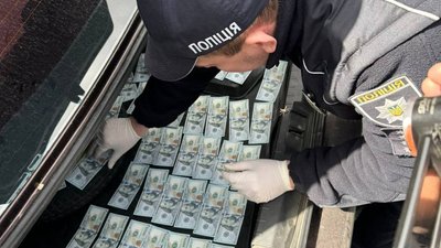 Працівник поліції проводить обшук автівки підозрюваного Працівник поліції проводить обшук автівки підозрюваного