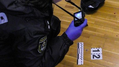 Працівниця поліції фіксує речові докази на місці події