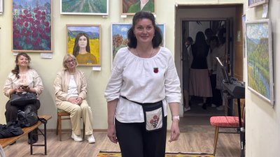 Учасниця демонструє вишиту сорочку під час показу