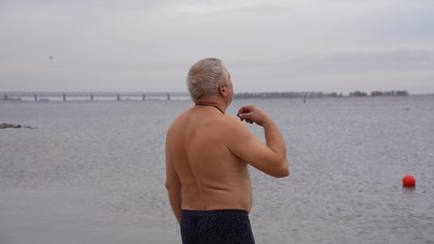 Чоловік хреститься перед тим, як зайти у Дніпро, 6 січня 2024 року