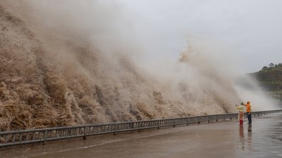 Люди дивляться на хвилі на набережній в Китаї