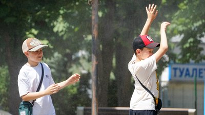 Хлопці стоять під водяним розпилювачем