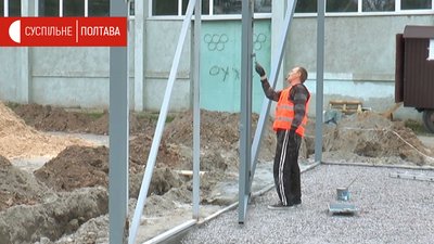 Працівник фарбує огорожу Працівник фарбує огорожу