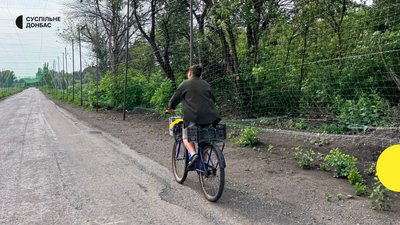 Жінка їде велосипедом сільською дорогою на Донеччині 25 липня 2026 року