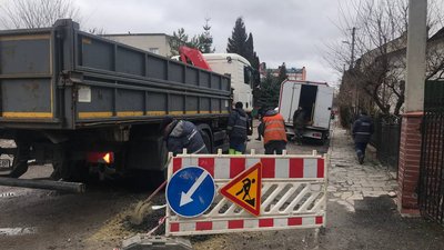 Працівники "Тернопільводоканалу" засипають яму біля каналізаційного колодязя на дорозі