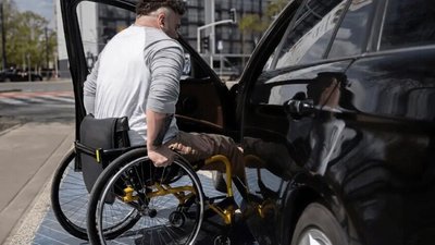Чоловік на кріслі колісному сідає в авто