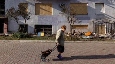Жінка з кравчучкою йде повз зруйнований обстрілом у вересні будинок у Краматорську