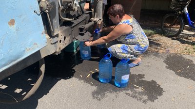 Жителька міста набирає воду, яку підвезли автоцистернами
