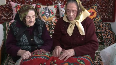 Мати і дочка тримають в руках килим, який вишивали разом Мати і дочка тримають в руках килим, який вишивали разом