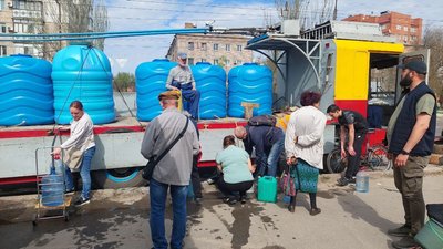 Люди набирають воду з бочок, що розвозить тролейбус, 2022 рік Люди набирають воду з бочок, що розвозить тролейбус, 2022 рік