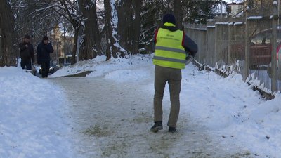 Комунальник посипає стежку Комунальник посипає стежку