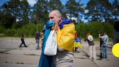Український військовий після обміну з українським прапором та прапором бригади