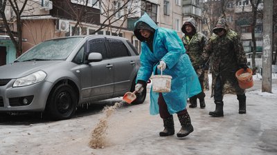 Двірничка посипає дорогу піском у Харкові