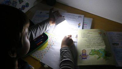 Дитина робить уроки під ліхтариком