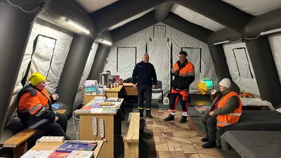 Працівниці комунальної служби зігріваються у мобільному пункті незламності ДСНС