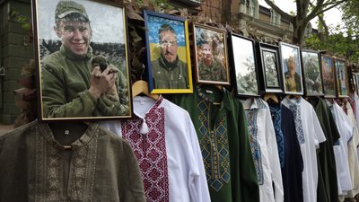 Світлини захисників, розміщені поруч із вишиванками на виставці