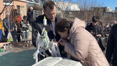 Жінка цілує стрічку з іменем свого сина