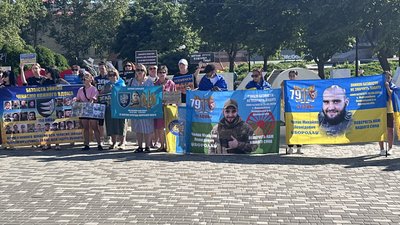 Люди з плакатами та прапорами під час хвилини мовчання у Миколаєві