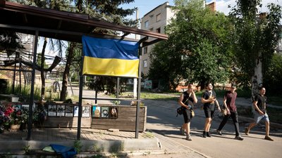 Люди йдуть вулицею біля розбитої обстрілом піцерії «РІА» в Краматорську 