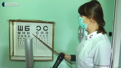 Медична сестра школи Анастасія Татарчук показує, що бачить Іван на таблиці лиш перших три ряди Медична сестра школи Анастасія Татарчук показує, що бачить Іван на таблиці лиш перших три ряди