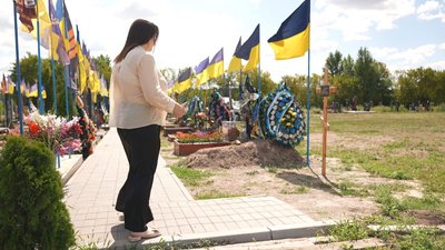 Аліна Отземко біля хреста з іменем її чоловіка