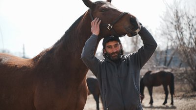 Волонтер Роберт Саргсян з конем на іподромі