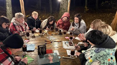 Вечірнє зібрання людей у колі із малюванням та теплими напоями