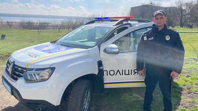 Поліцейський офіцер громади поруч зі службовою автівкою на Миколаївщині.