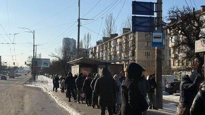 Люди чекають на громадський транспорт у Києві, зупинка