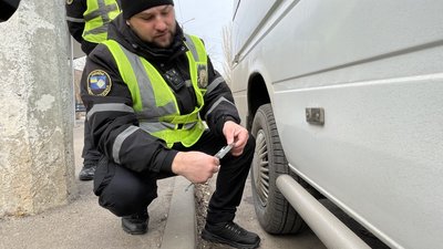 Андрій Процький перевіряє висоту гуми колеса автівки.