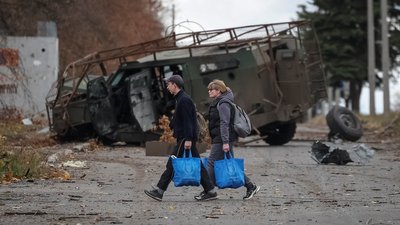 Люди йдуть вулицею поблизу зруйнованого броньованого військового автомобіля, Костянтинівка