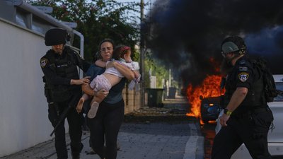 Поліцейські евакуюють жінку та дитину з місця, в яке влучила ракета з сектора Газа
