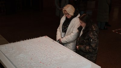 Жінки біля моделі масового поховання в Ізюмі на виставці в Києві