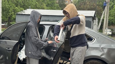 Жінка й чоловік закривають плівкою вибите вікно автомобіля, Салтівський район