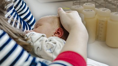 Мати годує немовля грудним молоком