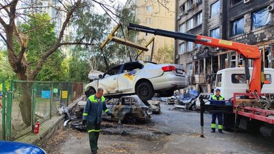 Столичні комунальники прибирають з дворів пошкоджені атакою РФ автівки