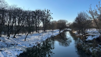 Весняний пейзаж із річкою, що протікає між засніженими берегами