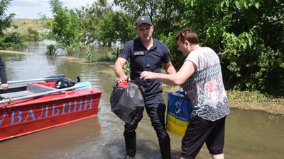 Рятувальник допомагає евакуювати жінку Рятувальник допомагає евакуювати жінку