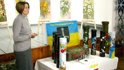 Художниця презентує розписані нею гільзи, тубуси і ящик для снарядів