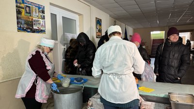 Люди в черзі по гарячу їжу в пункті незламності у Харкові