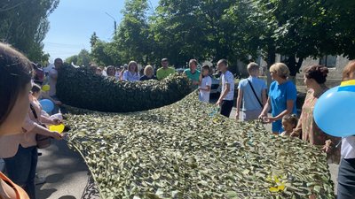 Волонтери тримають маскувальну сітку Волонтери тримають маскувальну сітку