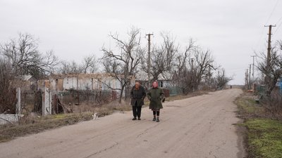Літні жінки та кішка прогулюються зруйнованим селом Літні жінки та кішка прогулюються зруйнованим селом