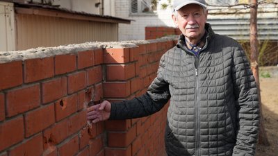 Житель Харкова Микола Ткачов показує дірки у цеглі після удару по Слобідському району БпЛА