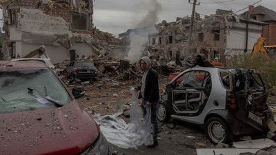 Чоловік готується накрити пошкоджений автомобіль пластиковою плівкою 