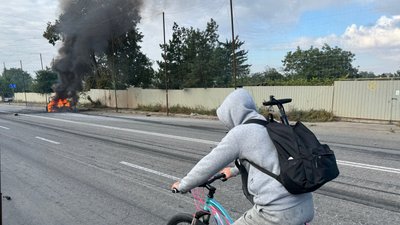 Чоловік їде дорогою в Краматорську, де палає авто після російського удару