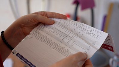 Жінка тримає квитанцію за комунальні послуги