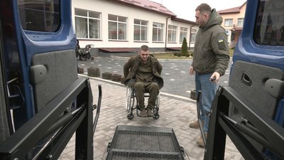 Поранений боєць заїжджає в таксі на кріслі колісному Поранений боєць заїжджає в таксі на кріслі колісному