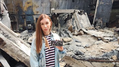 Юлія Логовська на телефоні показує фото підприємства до ракетної атаки