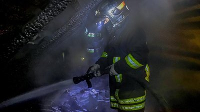 Рятувальник гасить пожежу в будинку