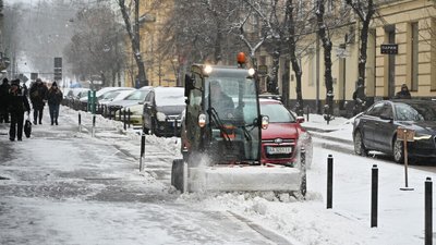 Комунальник прибирає тротуар від снігу
